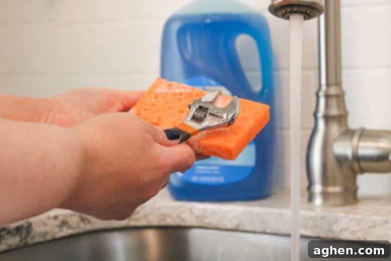 A greasy wrench being meticulously cleaned with a sudsy sponge, highlighting Dawn's ability to cut through tough grime