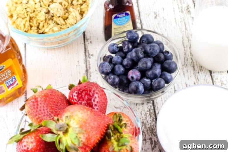 A bottle of vanilla extract and bowls of granola, blueberries, milk, yogurt, and strawberries.