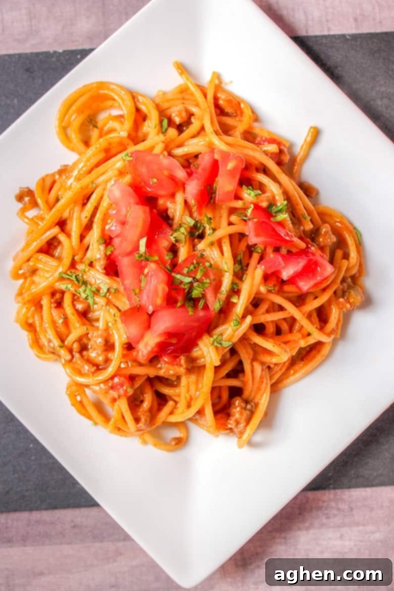 Close-up of One-Pot Taco Spaghetti topped with fresh diced tomatoes and cilantro, showcasing melted cheese
