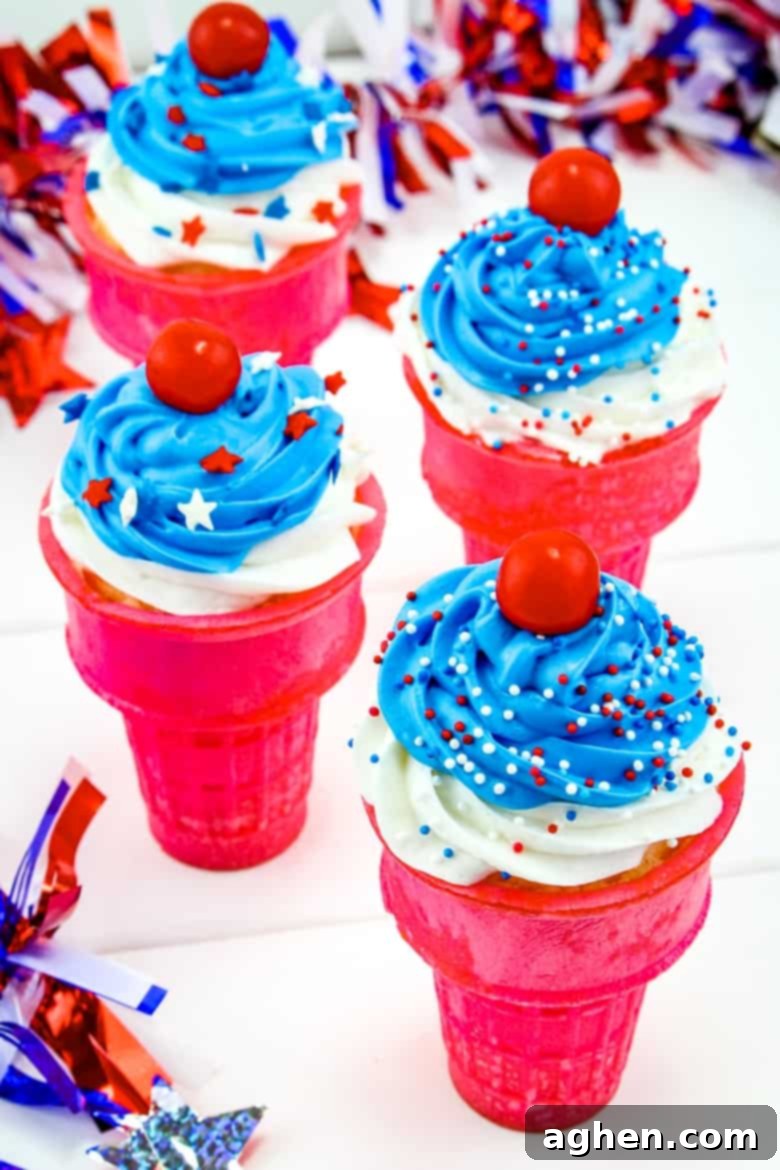 Red, white, and blue ice cream cone cupcakes adorned with patriotic sprinkles and a red candy on top, displayed against a rustic background. A perfect 4th of July dessert.