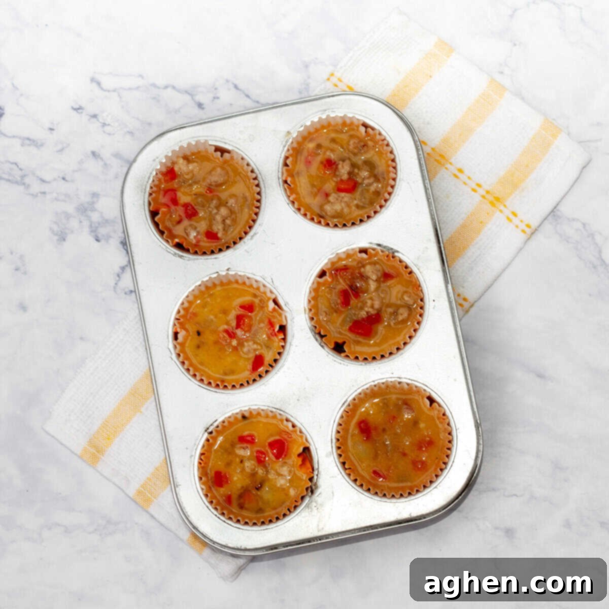 Weight Watchers Pork Egg Bites: Effortless On-the-Go Breakfast Solution 7 The pork and egg mixture being carefully spooned into a greased 6-cup muffin tin, with shredded cheese sprinkled on top.