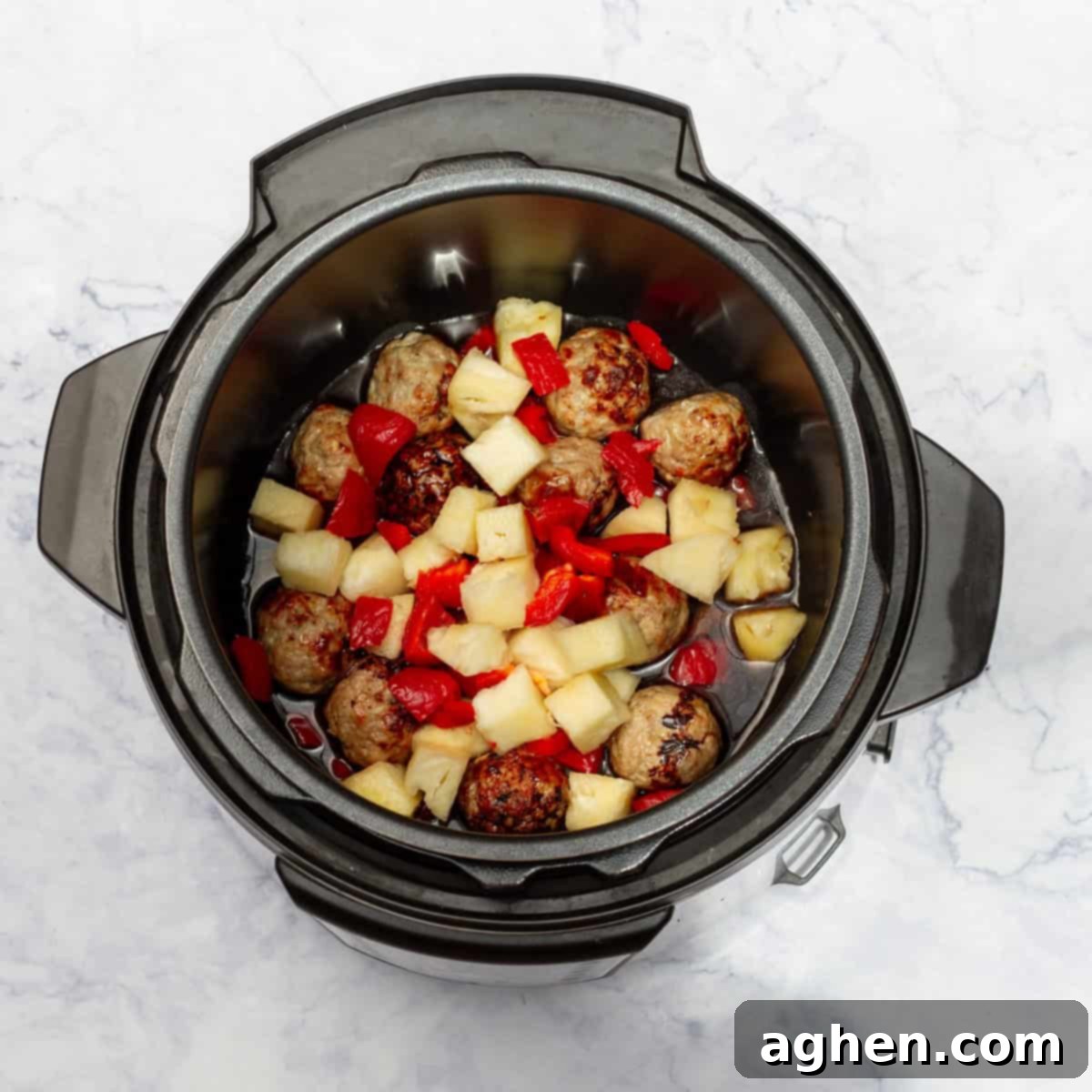Diced red bell pepper and pineapple chunks in the Instant Pot, forming the sauce base