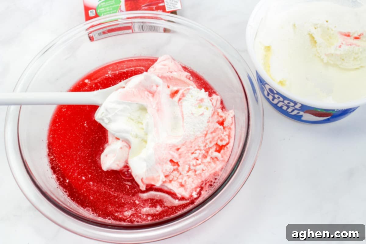 Effortless Strawberry Gem Pie 5 Cool Whip being mixed into jello mixture.