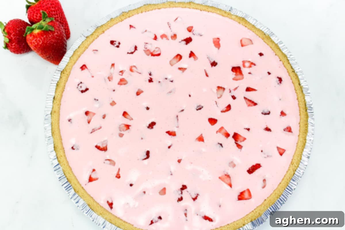 Effortless Strawberry Gem Pie 6 pink pie with strawberries in it in a graham cracker crust.