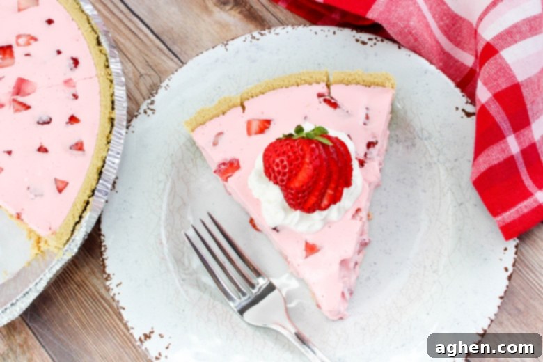 Effortless Strawberry Gem Pie 7 Slice of Strawberry Jello Pie on white plate, garnished with whipped cream and strawberries