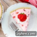 Effortless Strawberry Gem Pie 10 Slice of Strawberry Jello Pie on white plate, garnished with whipped cream and strawberries