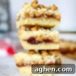 Nostalgic Peanut Butter & Jelly Squares 7 A single Peanut Butter and Jelly cookie bar, showcasing its distinct layers and appealing texture on a small plate, ready to be sampled.