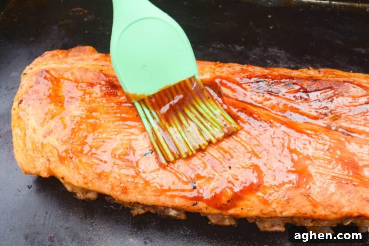 Achieving Perfect Ribs on Your Blackstone Griddle 11 A close up of a green silicone brush adding barbecue sauce to the cooked ribs on the Blackstone