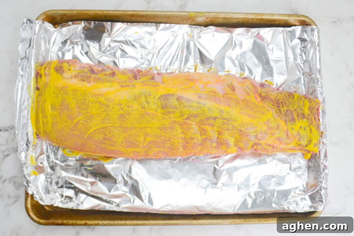 Achieving Perfect Ribs on Your Blackstone Griddle 6 A large baking sheet lined with tinfoil. The uncooked ribs are coated in bright yellow mustard