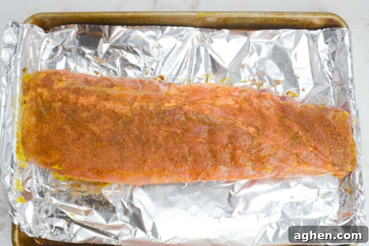Achieving Perfect Ribs on Your Blackstone Griddle 7 A large baking sheet lined in foil. The uncooked ribs are light brown from the dry rub