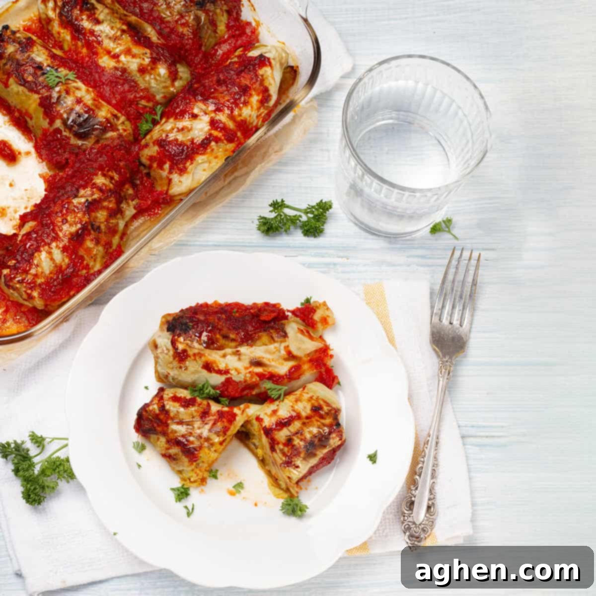 Delicious baked Pork Cabbage Rolls served on a pristine white plate, garnished with fresh, vibrant parsley for a touch of color.