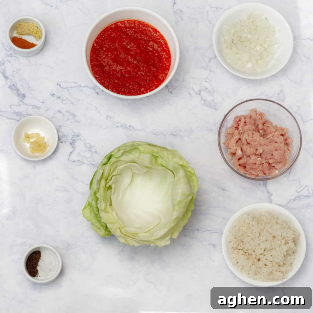 A vibrant collection of fresh ingredients laid out on a wooden surface, including lean ground pork, green cabbage, red onion, garlic cloves, cooked rice, and a jar of rich marinara sauce, all prepared for making delicious cabbage rolls.