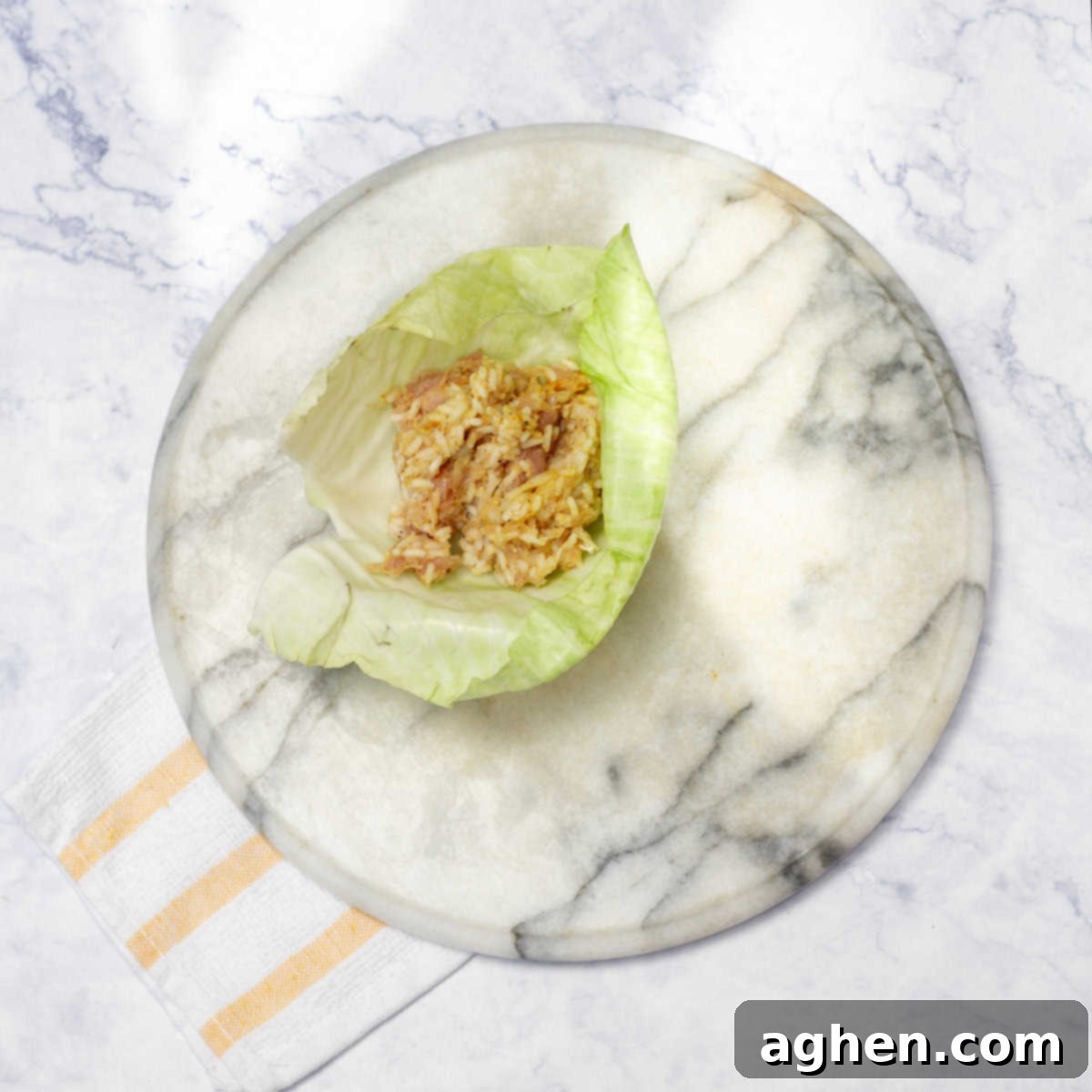 A single, perfectly softened cabbage leaf laid flat, precisely filled with a generous portion of the savory pork and rice mixture, poised for the meticulous rolling process.