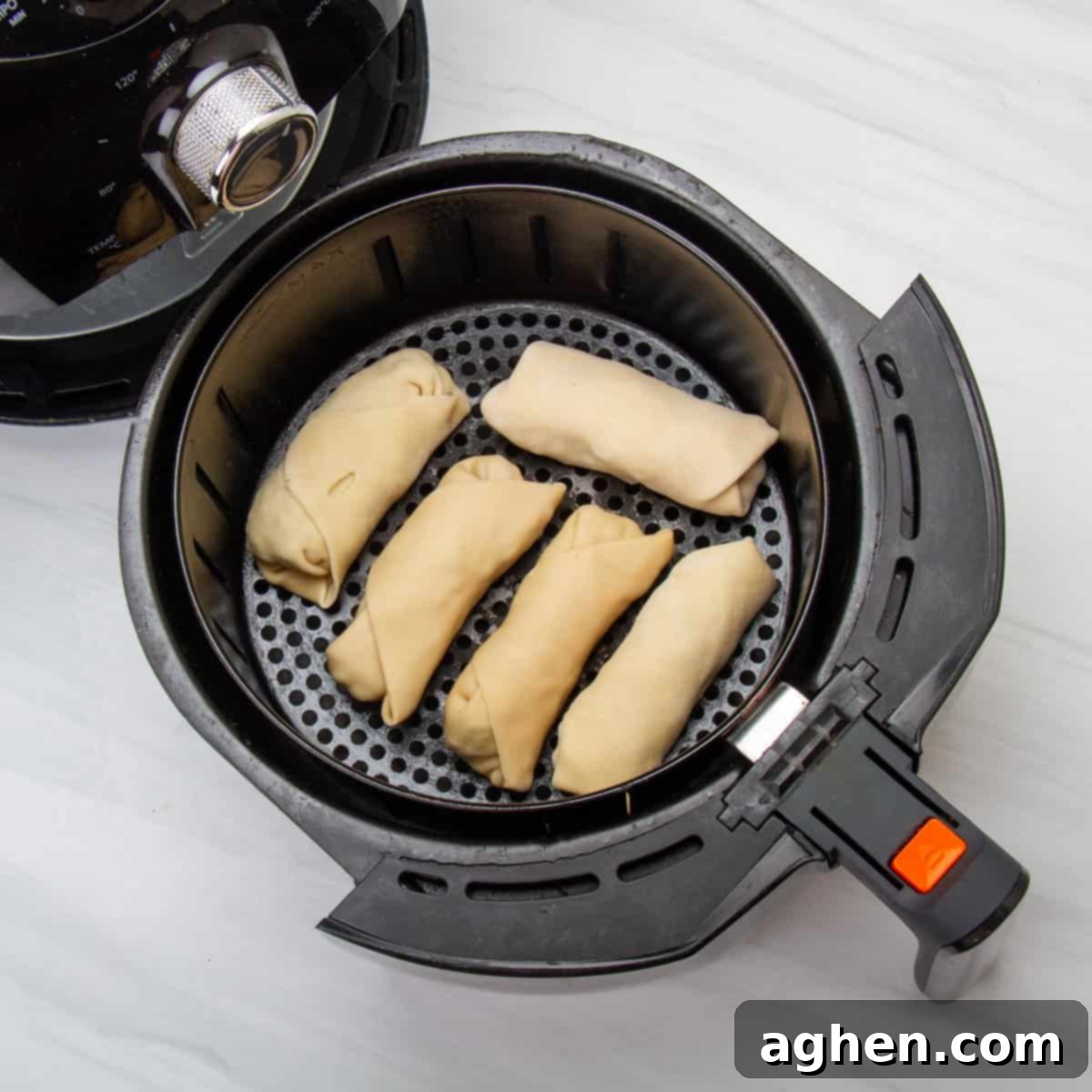 Ditch Takeout for These Weight Watchers Pork Egg Rolls 8 Multiple raw pork egg rolls neatly arranged in a single layer within an air fryer basket, ready for cooking to golden perfection.