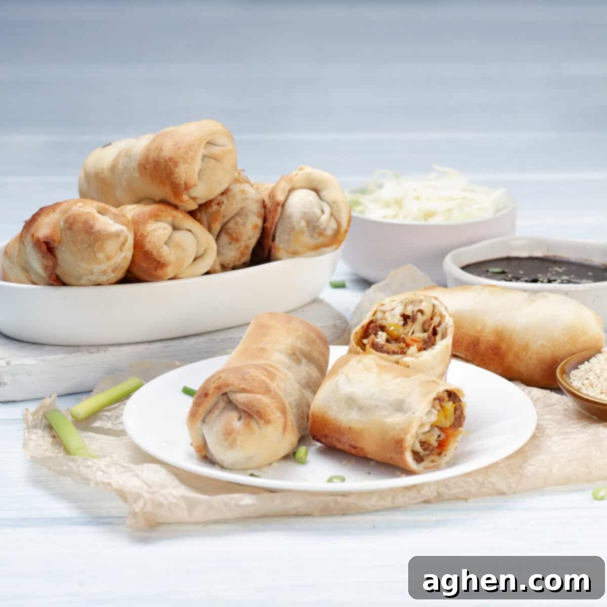 Ditch Takeout for These Weight Watchers Pork Egg Rolls 9 Freshly cooked, golden-brown Air Fryer Pork Egg Rolls presented in a stylish serving dish, accompanied by a small bowl of dipping sauce and a baking tray of additional egg rolls in the background.