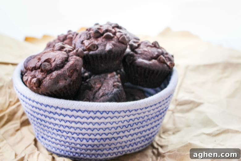 Ultimate Double Chocolate Banana Muffins 3 Blue and white woven bowl filled with chocolate muffins with chocolate chips.