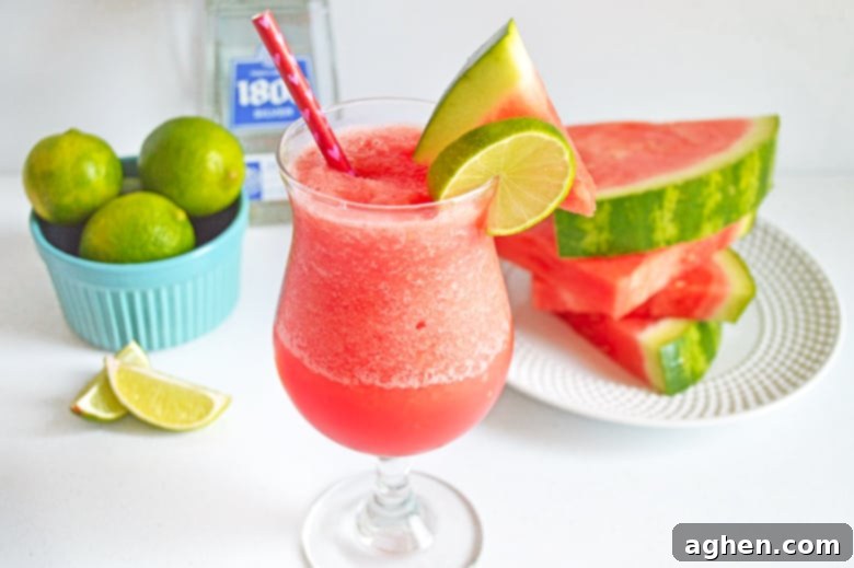 Ingredients for a frozen watermelon margarita laid out: fresh watermelon slices, a bottle of silver tequila, and a bowl of fresh limes.