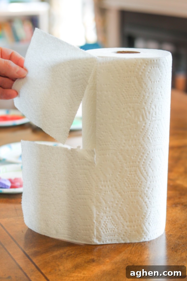 Close-up of hands tearing a quarter-size square from a roll of Brawny® Tear-A-Square® paper towels, demonstrating its unique perforated design.
