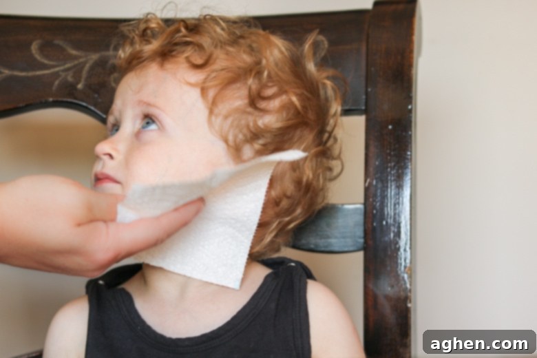 A gentle hand wiping paint from a child's cheek with a soft, strong Brawny® Tear-A-Square® paper towel, highlighting easy cleanup of small messes.