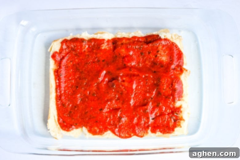 Buns in casserole dish with marinara sauce on top.