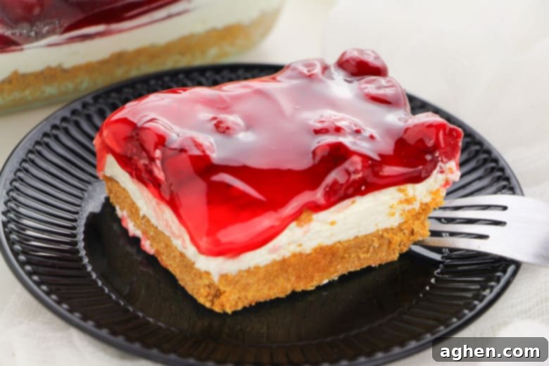 Slice of No Bake Cherry Cheesecake on a white plate with a fork