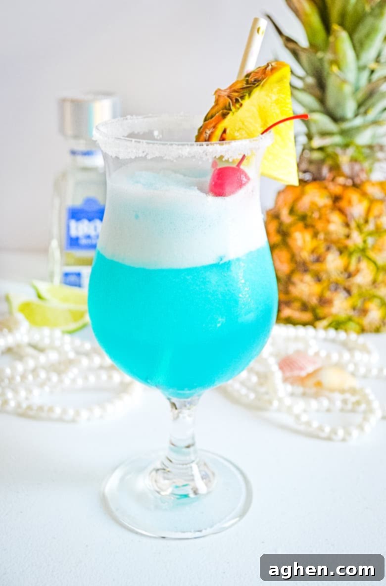 Frozen blue cocktail garnished with fresh pineapple and maraschino cherry, ready to be enjoyed on a hot day