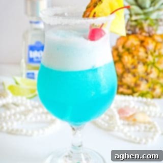 Frozen blue cocktail garnished with fresh pineapple and maraschino cherry