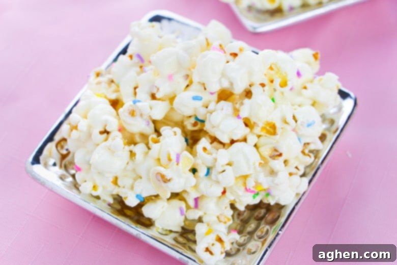 Cake batter popcorn topped with rainbow sprinkles and served on a flat silver plate.