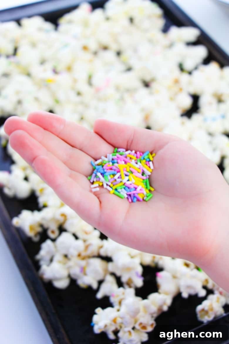 Woman's hand holding sprinkles over tray of popcorn