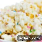 Cake batter popcorn topped with rainbow sprinkles and served on a flat silver plate.
