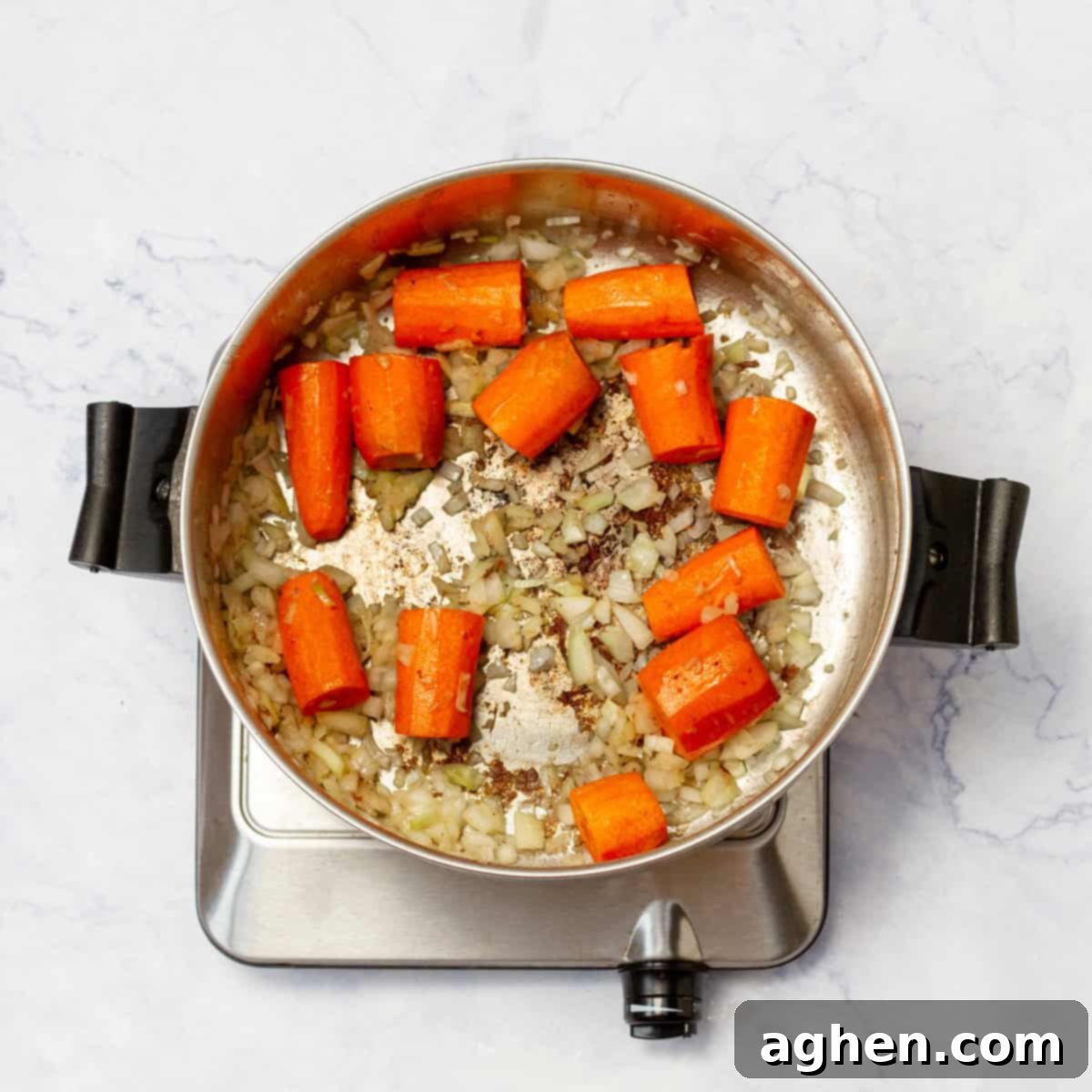 chopped onion and carrots cooking in a pan