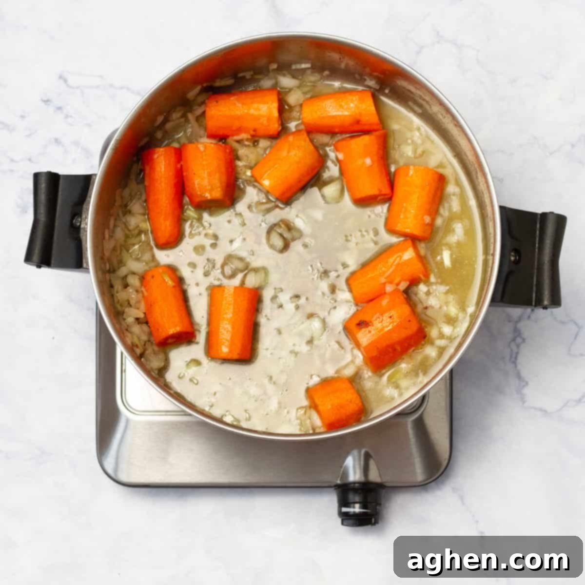 chopped onion and carrots cooking in a pan