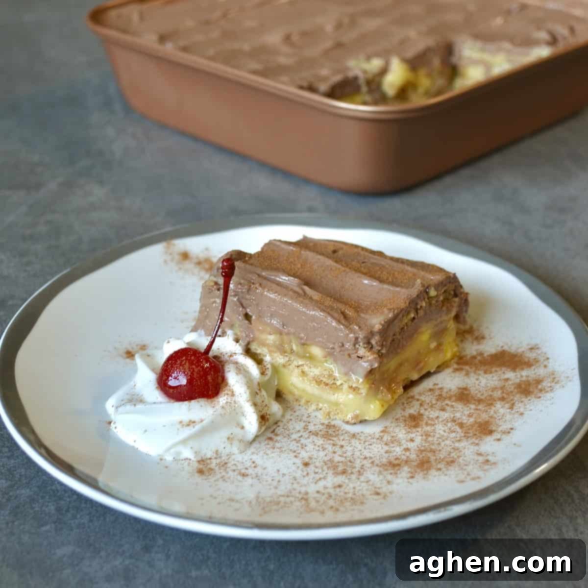 A perfectly sliced piece of chocolate banana icebox cake, showing layers of graham crackers, banana pudding, fresh bananas, and chocolate yogurt