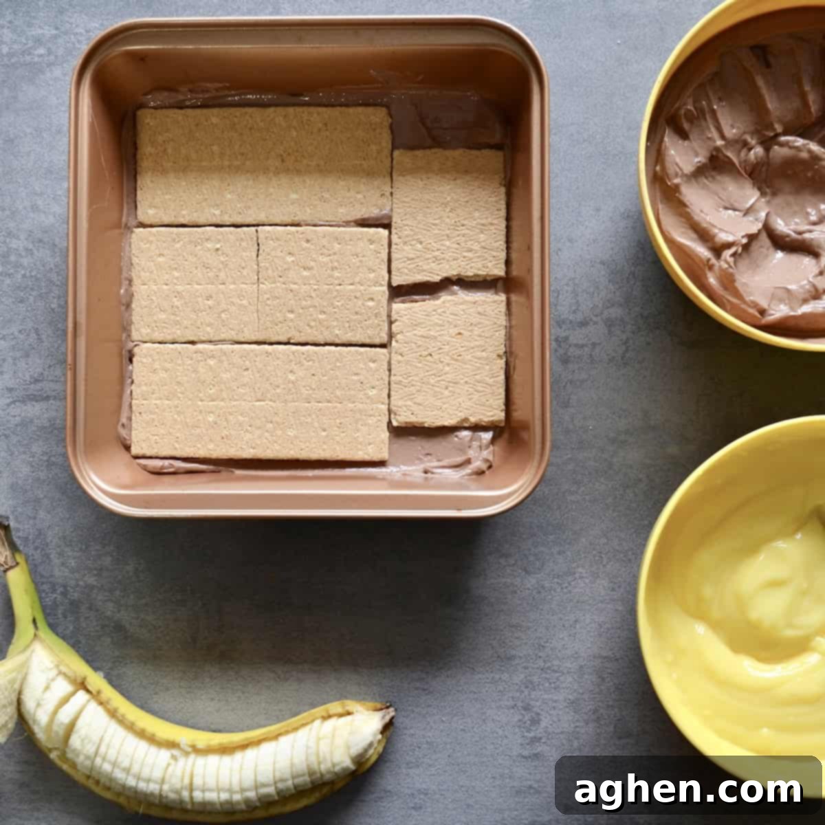 Initial layer of chocolate yogurt spread thinly at the bottom of an 8x8 baking dish for the icebox cake