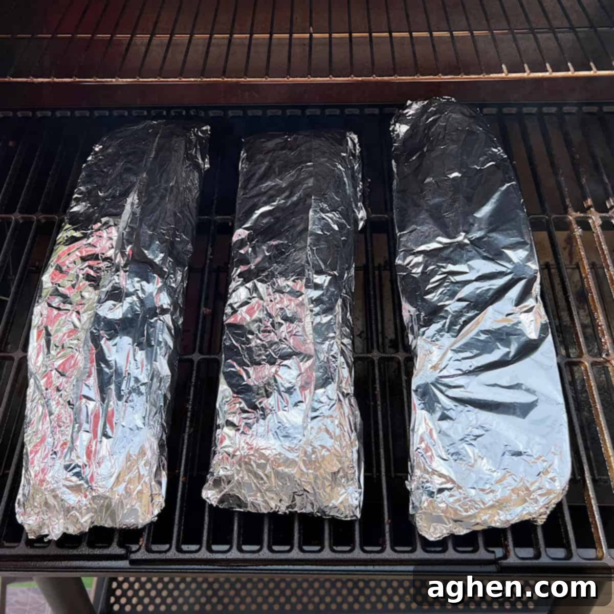 Award Winning Smoked Baby Back Ribs 11 Foil-wrapped ribs placed back on the grill grate of the smoker.