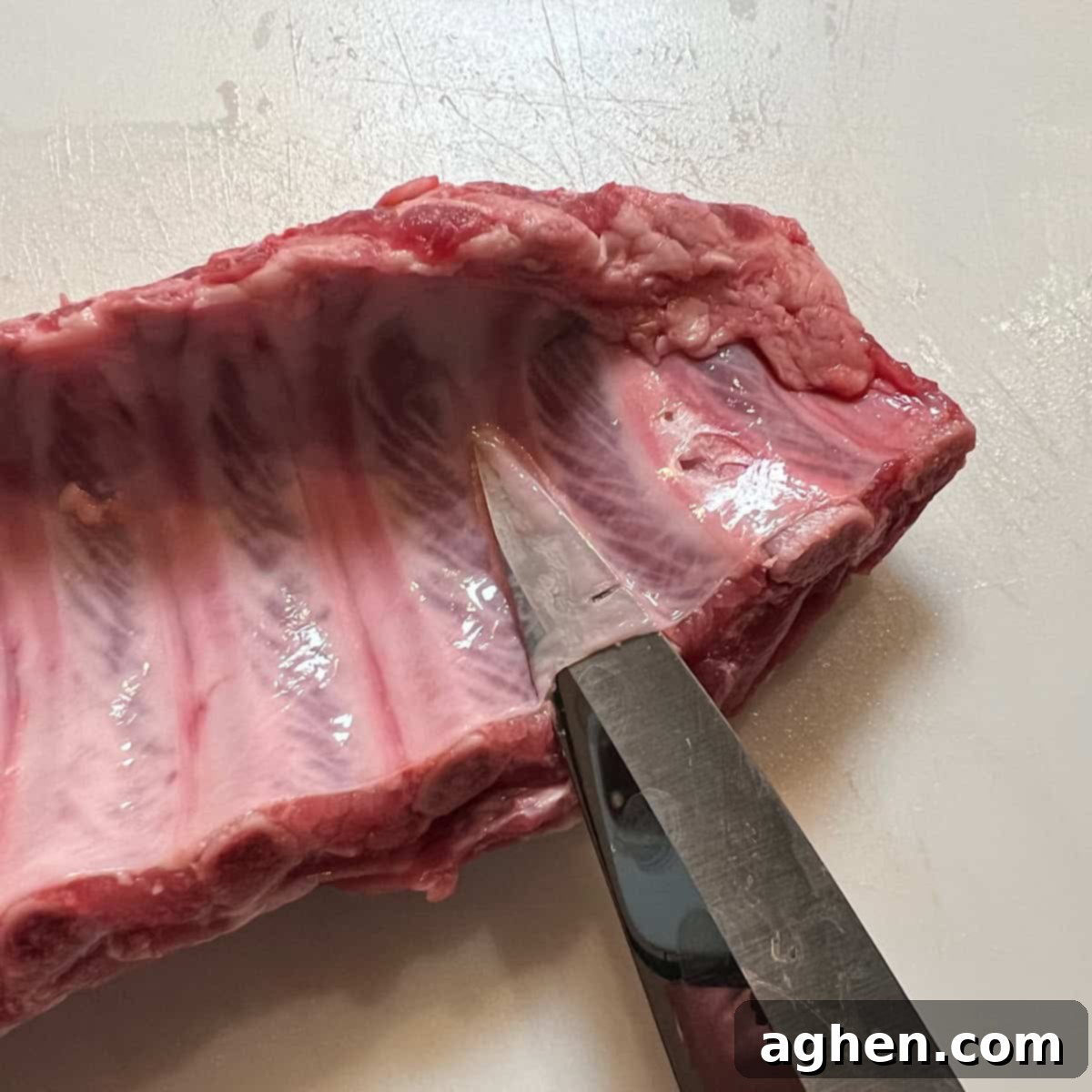 Award Winning Smoked Baby Back Ribs 4 Using a knife to gently lift the membrane from the underside of baby back ribs.