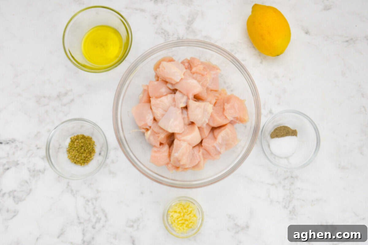 Small glass bowls neatly arranged, each filled with one of the key ingredients for the chicken souvlaki recipe, highlighting fresh lemon, dried oregano, minced garlic, and olive oil, showcasing the simplicity of the components.