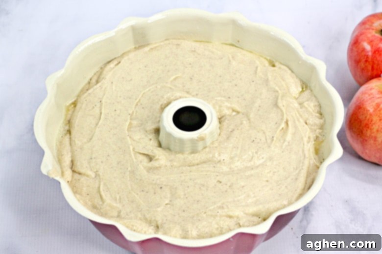 Apple cider cake batter poured and smoothed into a bundt pan, ready for baking