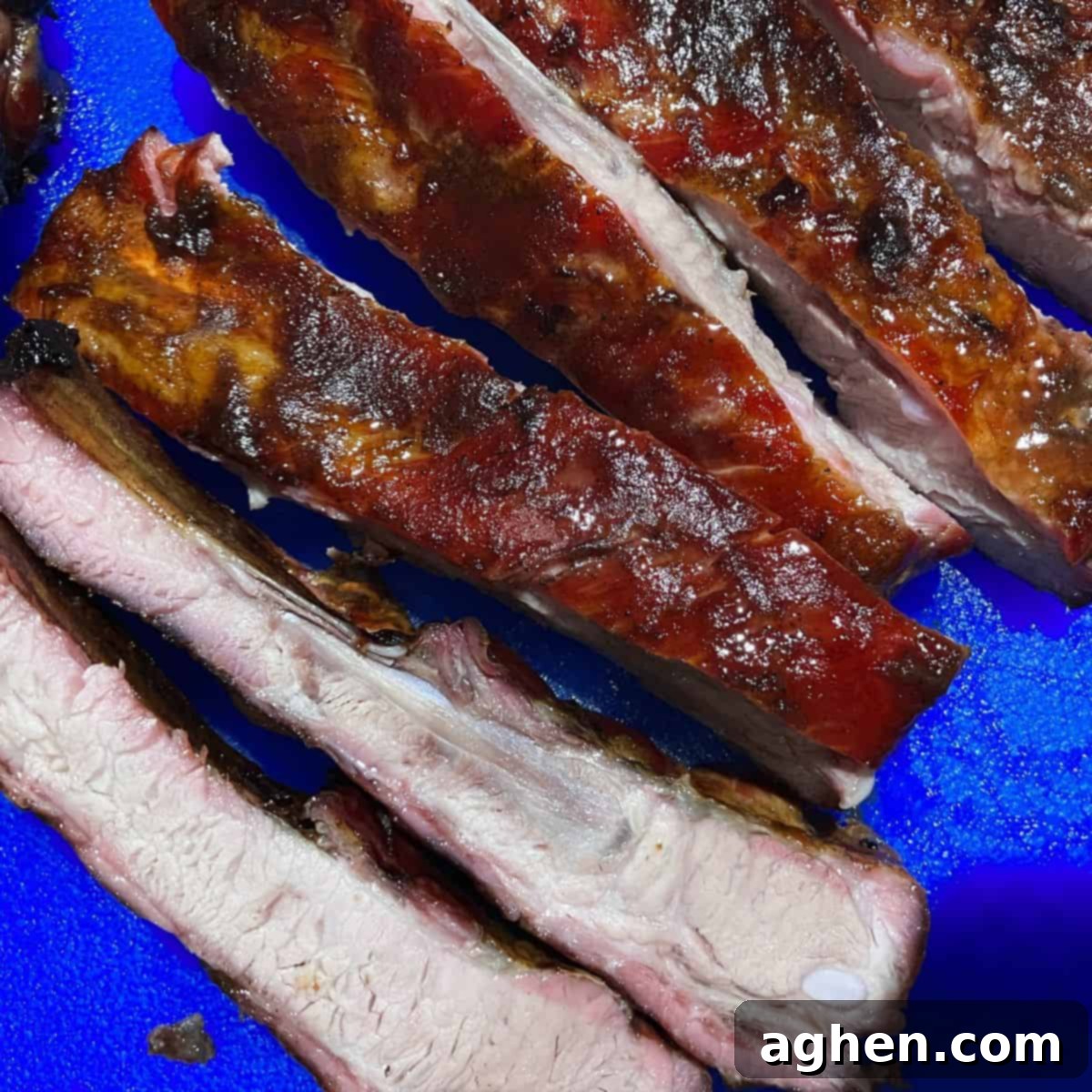 Masterbuilt Smoker Secrets for Irresistible Ribs 2 Cooked ribs cut and ready to eat sitting on blue cutting board.