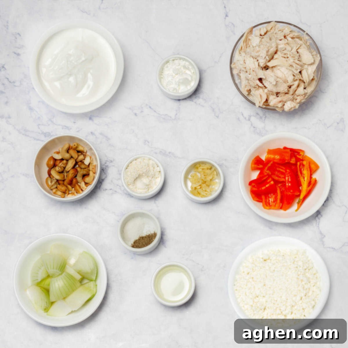 Ingredients for Peruvian Aji de Gallina: shredded chicken breast, yellow ají peppers (or paste), onion, minced garlic, spices, Parmesan cheese, Greek yogurt, cottage cheese, cashews, and cornstarch. 
