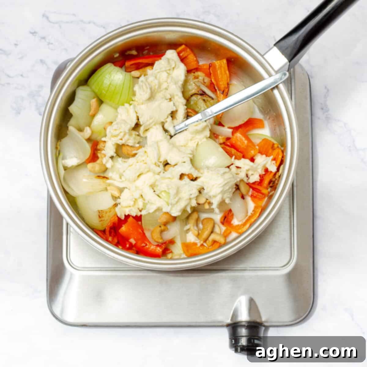 Adding Greek yogurt, cornstarch slurry, Parmesan cheese, and cashews to the cooked aromatics to create the creamy Ají de Gallina sauce. 