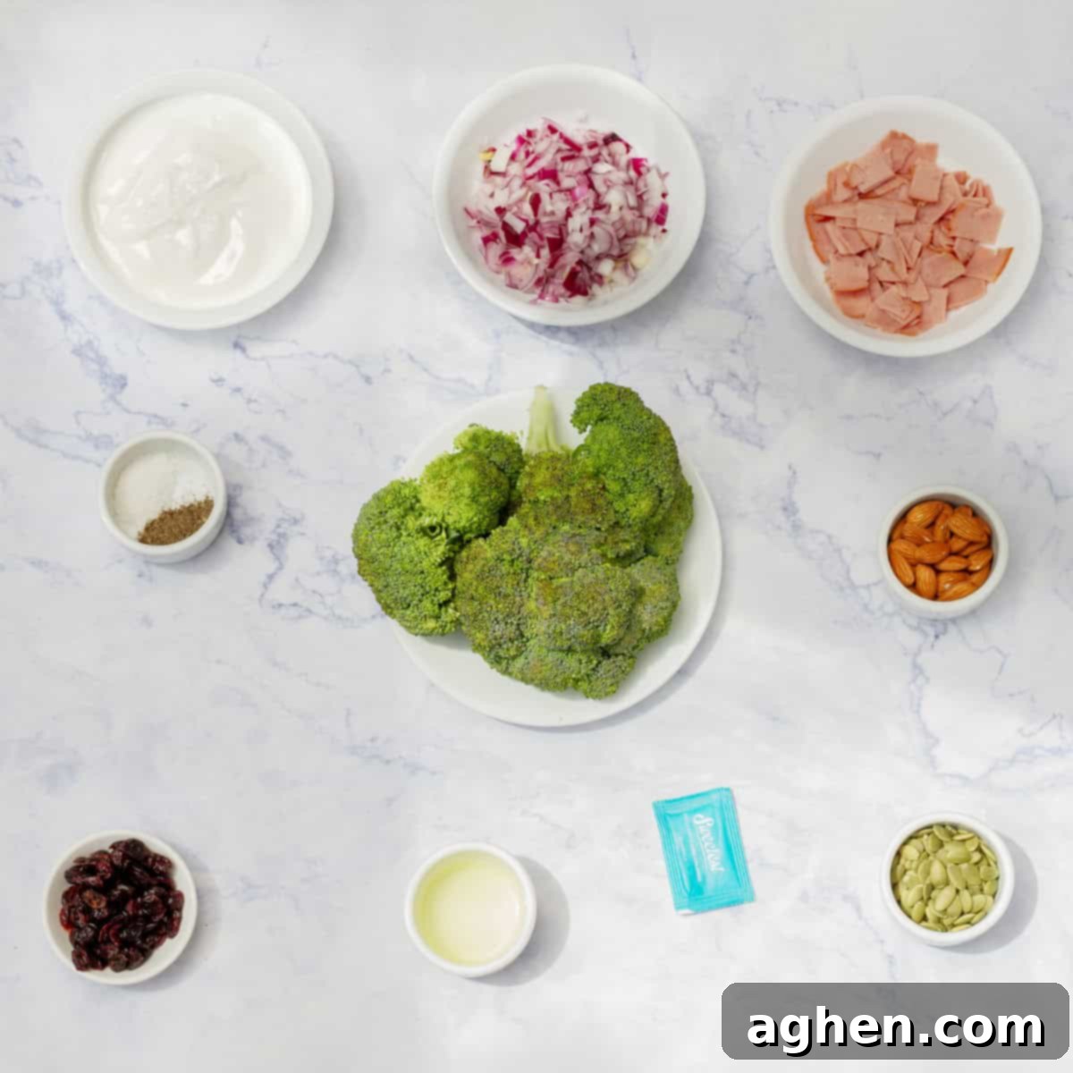 Broccoli salad ingredients of raw broccoli, chopped ham, red onion, dried cranberries, chopped nuts, Greek yogurt, and seasonings. 