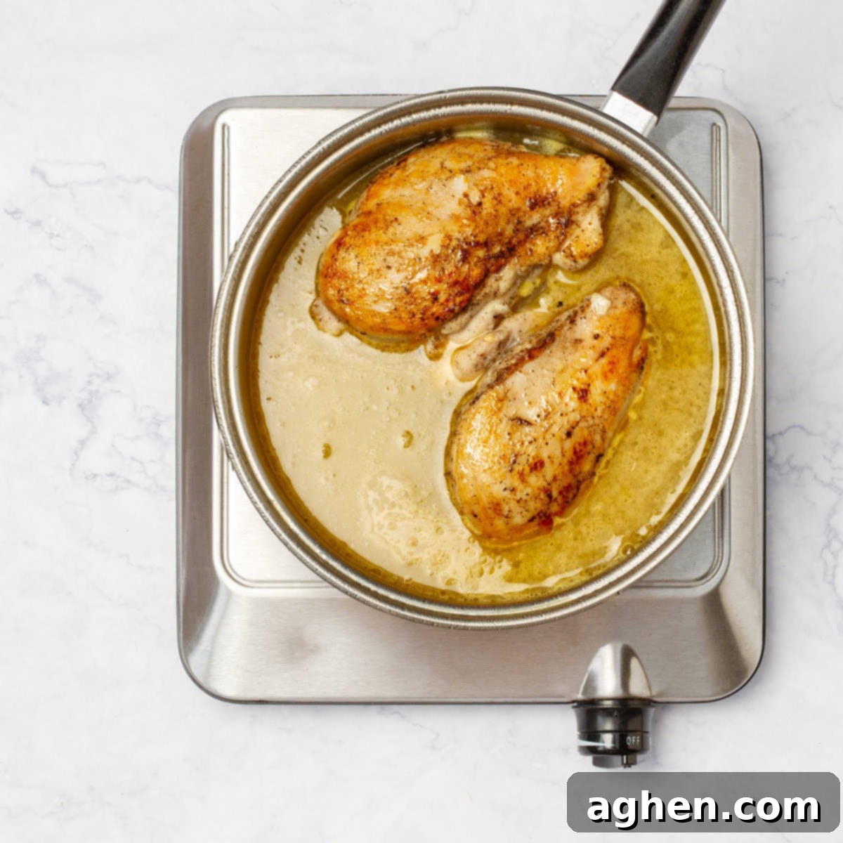 Searing chicken breasts simmering in unsweetened orange juice in a pan, tenderizing and infusing flavor.