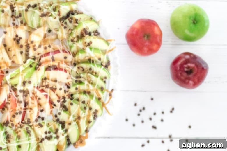 Vibrant Caramel Apple Nachos featuring red and green apple slices, generously drizzled with golden caramel, rich melted chocolate, a scattering of mini chocolate chips, and crunchy chopped pecans, all artfully arranged on a platter.