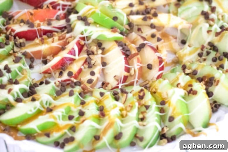 A close-up of Loaded Caramel Apple Slices, featuring a rich assortment of melted white chocolate, luscious caramel sauce, fluffy mini marshmallows, and crunchy chopped nuts, piled high on a serving platter.