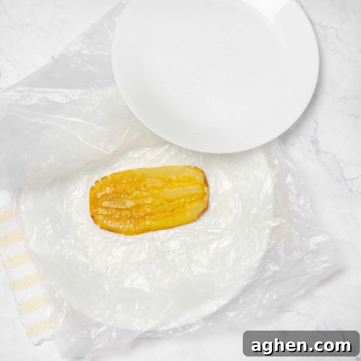 Par-fried plantain sliced and flattened on a dish lined with plastic wrap. 