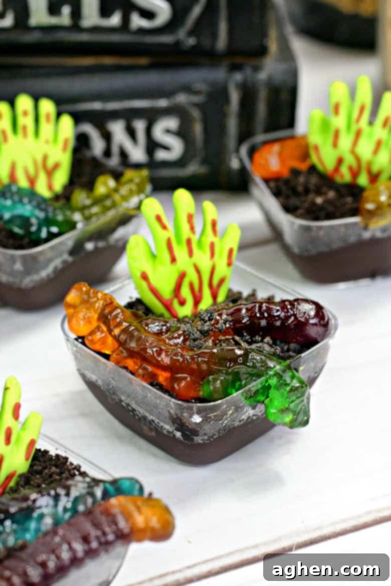 Halloween Pudding Cups showcasing spooky zombie hands emerging from chocolate pudding 'dirt' with gummy worms