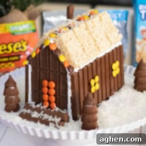 A charming Christmas candy house crafted from KitKat Bars, Hershey's Bars, Reese's Pieces, Reese's Peanut Butter Cups, and Rice Krispies Treats, ready for display.