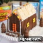 A festive Christmas candy house made with chocolate bars, Kit Kats, Reese's Peanut Butter Cups, Hershey's Kisses, and Rice Krispie Treats.