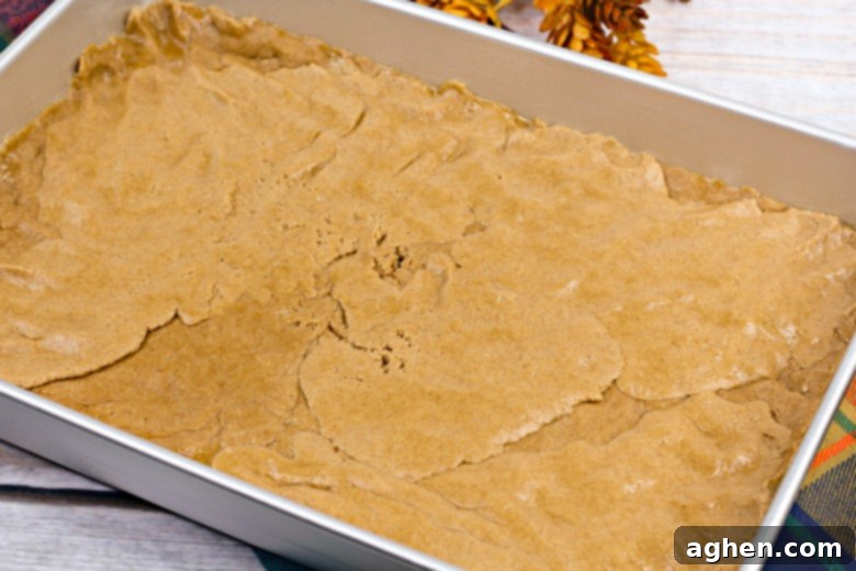 The unbaked harvest spice bar dough pressed into a parchment-lined baking pan, ready for the topping.